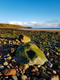 Stones on rocks in water against sky