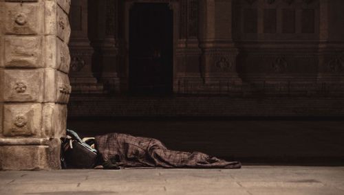 Refugee sleeping in building corridor on sunny day