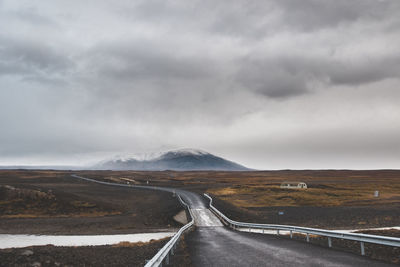 Country road amidst landscape against sky