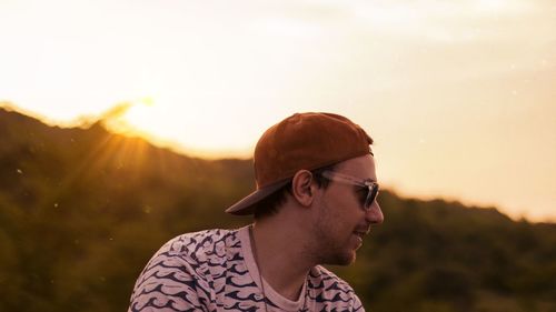 Young man looking away against sky during sunset