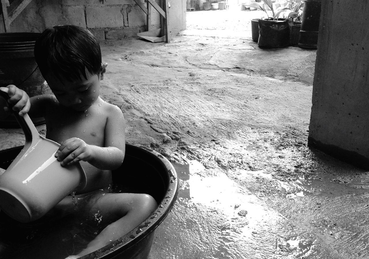 BOY PLAYING WITH WATER IN CONTAINER