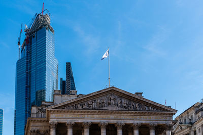 The royal exchange against skyscraper under construction in the city of london a sunny day