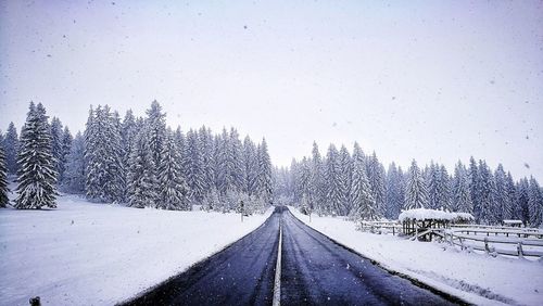 Snow covered road against clear sky during winter