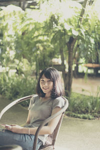 Portrait of smiling young woman against trees