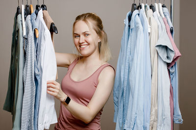 Portrait of smiling woman holding clothes in wardrobe