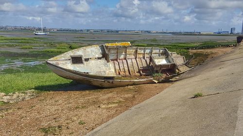 Abandoned boats moored on beach against sky