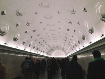 Low angle view of silhouette people walking in illuminated corridor