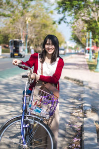Portrait of woman with bicycle standing on road