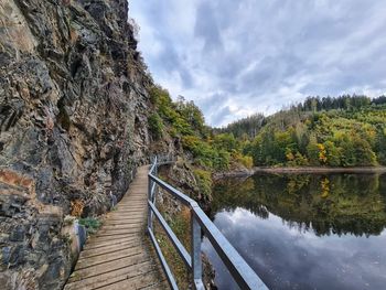 Footbridge over lake against sky