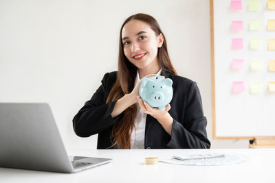 Portrait of smiling young businesswoman using laptop on table