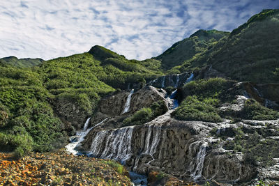 Low angle view of waterfall on rocks