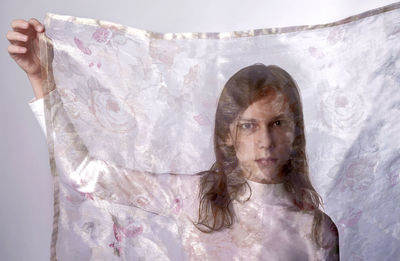 Portrait of young woman standing against wall