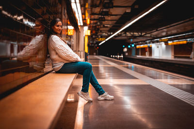 Side view of woman sitting at railroad station platform