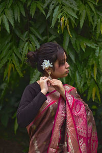 Young woman standing by flowering plants