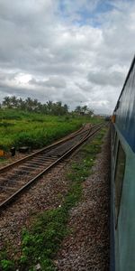 Train on railroad track amidst field against sky