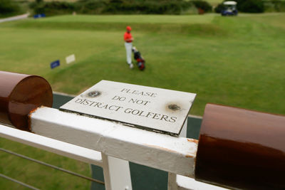 Sign saying please do not distract golfers with blurred golfer and golf cart in background 