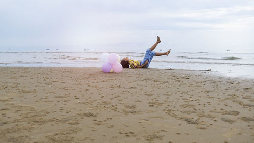 Asian young girl enjoy time playing balloone at the beach.