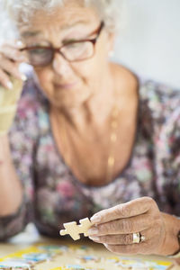 Senior woman solving jigsaw puzzle at table in nursing home