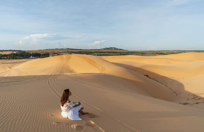 Rear view of woman walking on sand dune