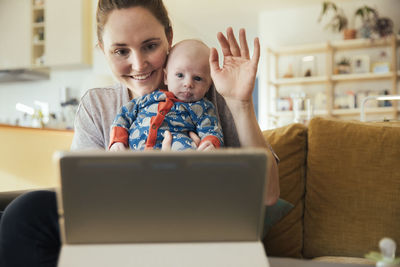 Mother and newborn baby taking a video call at home