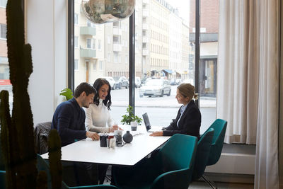 Couple discussing over documents with realtor in estate office