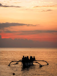 Silhouette people in boat at sunset