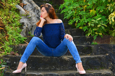 Low angle view of beautiful woman looking away while sitting on steps at park