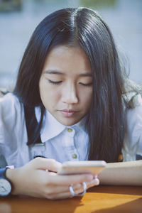 Close-up of girl using phone at table