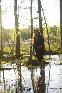 Woman standing by tree trunks in forest