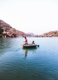 Men in boat on lake against clear sky