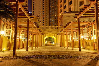 Illuminated street amidst buildings in city at night