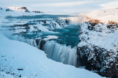 Scenic view of waterfall against sky during winter