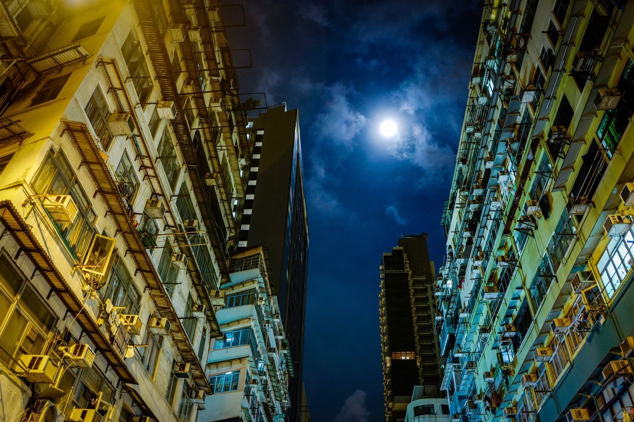 LOW ANGLE VIEW OF ILLUMINATED SKYSCRAPERS AGAINST BLUE SKY