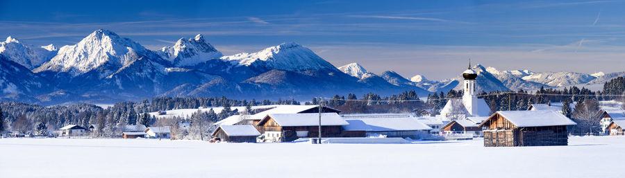 Snow covered buildings and mountains against sky