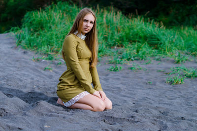 Portrait of young woman sitting on sand