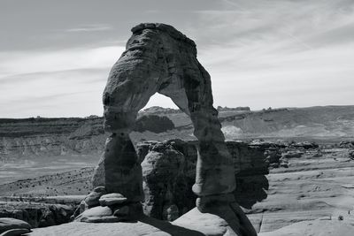 Arch shaped rock formation against sky