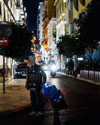 Rear view of man on illuminated street at night