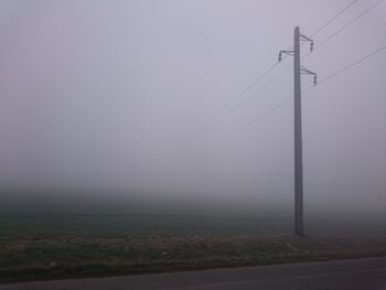 Electricity pylon on field against sky