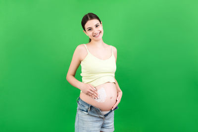 Portrait of a smiling young woman against green background