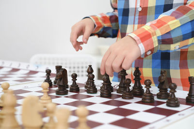 Closeup hand caucasian boy playing chess. happy concentrated child behind chess in class or school
