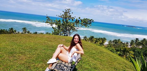 Portrait of beautiful woman standing at beach against sky