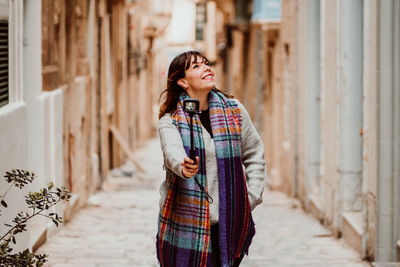 Woman holding monopod standing in alley