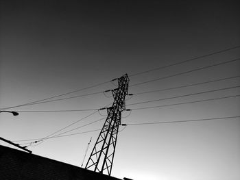 Low angle view of silhouette electricity pylon against clear sky