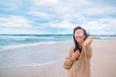 Portrait of smiling young woman standing on beach