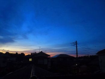 Silhouette electricity pylons against sky at sunset