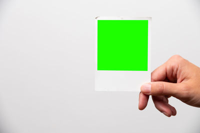 Cropped hand of person holding blank paper against gray background