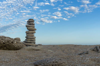 Stack of stones on rock against sky