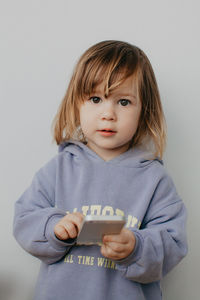 Portrait of cute girl standing against wall