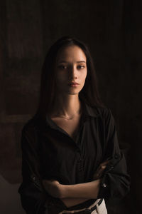 Portrait of woman standing against black background