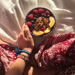 Low section of woman holding bowl with breakfast at home